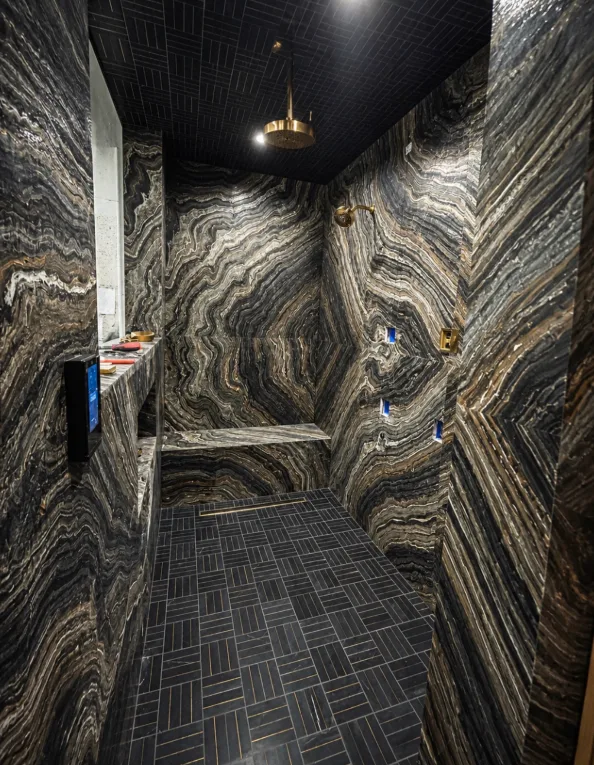 Book-matched onyx shower with bench & black mosaic floor