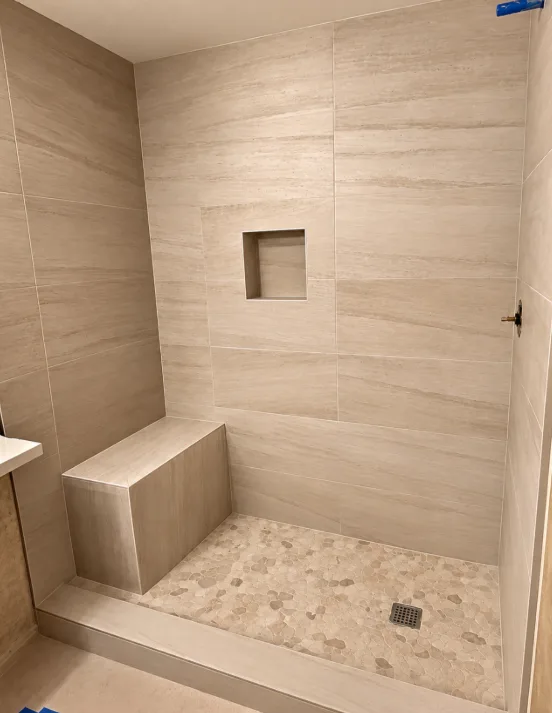 Travertine-look shower with bench & pebble pan